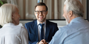 Ein Makler diskutiert und lacht mit einem älteren Ehepaar