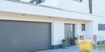 Einfamilienhaus mit weisser Fassade bei schönem Wetter
