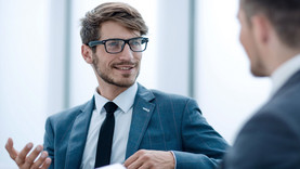 Makler mit Brille spricht mit einem Kollegen