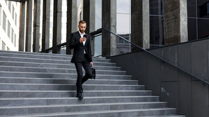 Makler läuft vor dem Bürogebäude die Treppe runter