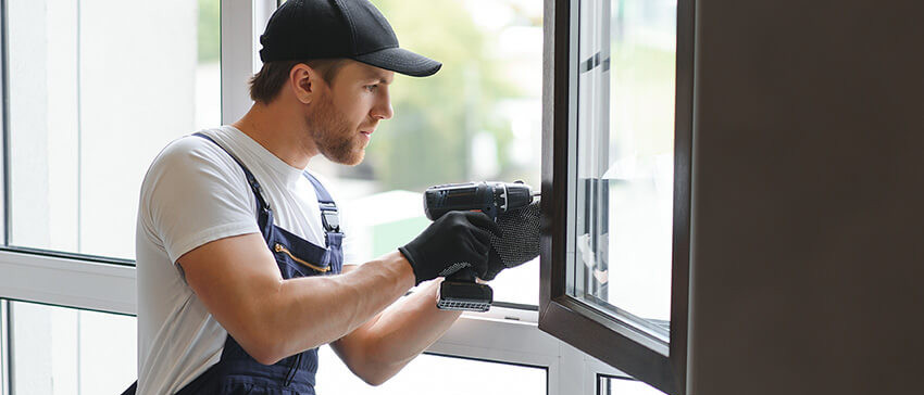 Junger Handwerker repariert Fenster in einer Wohnung