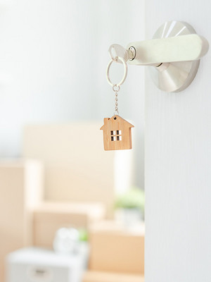 Schlüssel im Schlüsselloch mit offener Türe in die Wohnung