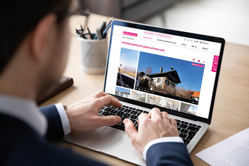Mann sitzt vor einem Laptop und sieht sich ein Immobilieninserat an