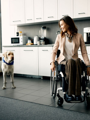 Frau im Rollstuhl mit einem Hund in ihrer Wohnung