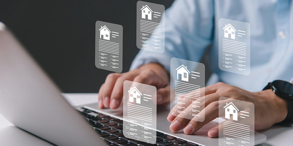 Mann tippt auf Laptop mit Immobilienicons