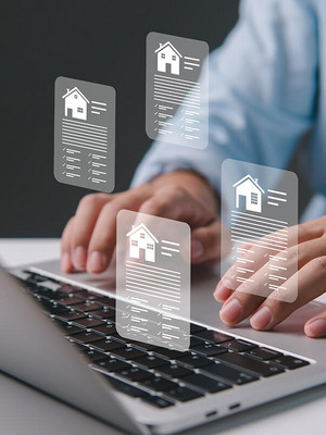 Mann tippt auf Laptop mit Immobilienicons