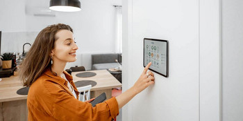 Junge Frau tippt auf ihrem Smart Home Tablet