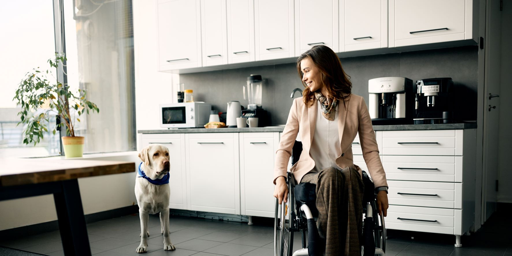 Frau im Rollstuhl mit einem Hund in ihrer Wohnung