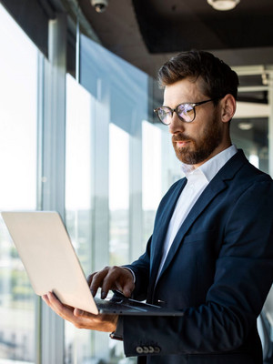 Makler steht mit Laptop in der Hand