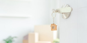 Schlüssel im Schlüsselloch mit offener Türe in die Wohnung