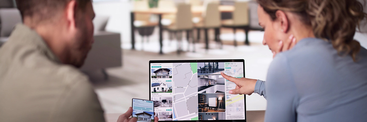 Paar zeigt auf Laptop mit Immobilieninseraten