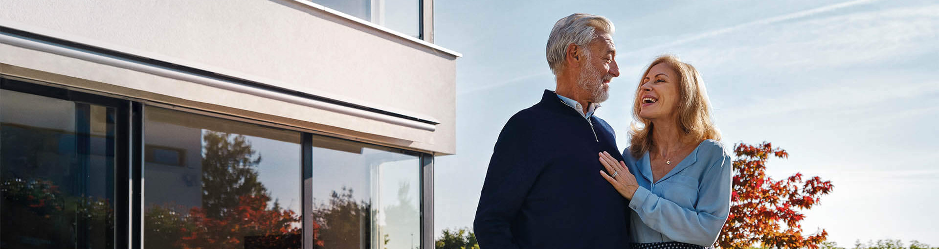 Glückliches Ehepaar steht vor schönem Haus und schaut sich verliebt an